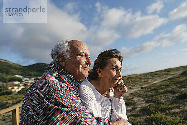 Lächelnde ältere Männer und Frauen unter bewölktem Himmel an einem sonnigen Tag