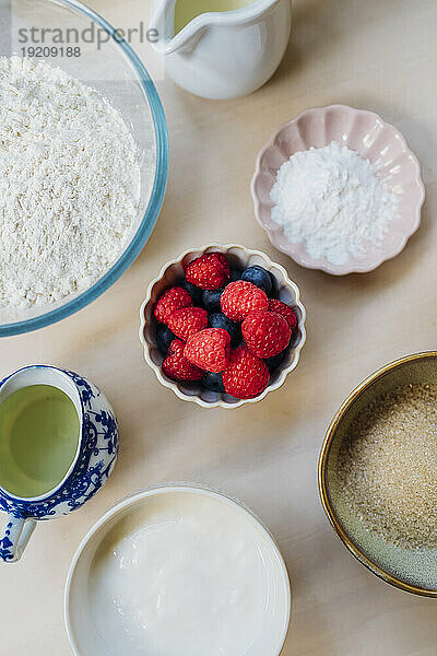 Bowl of fresh berries with ingredients on table