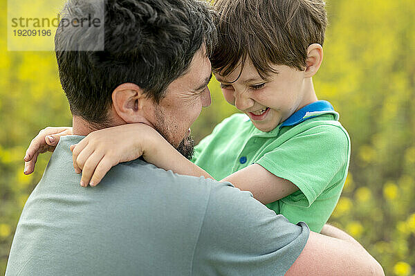 Glücklicher Vater umarmt Sohn auf dem Feld