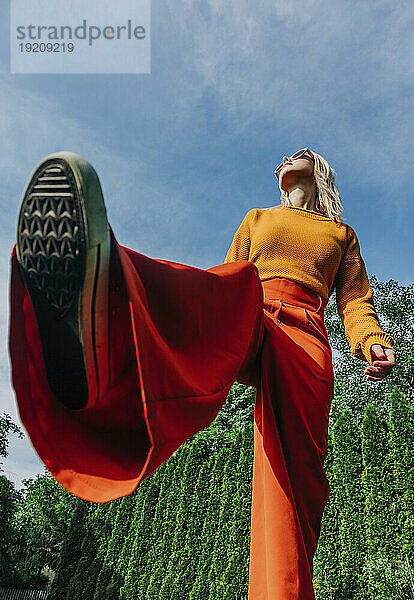 Blonde Frau steht auf einem Bein im Garten