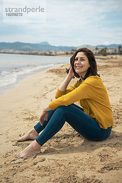 Glückliche Frau sitzt am Strand