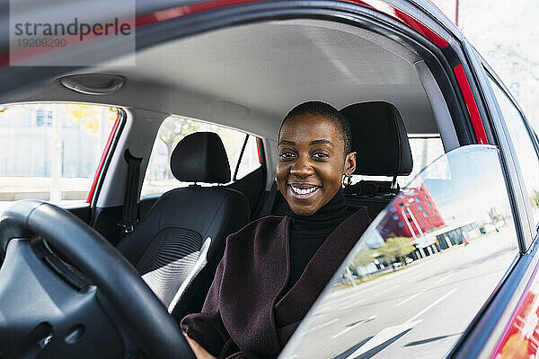 Glückliche junge Frau sitzt im Auto