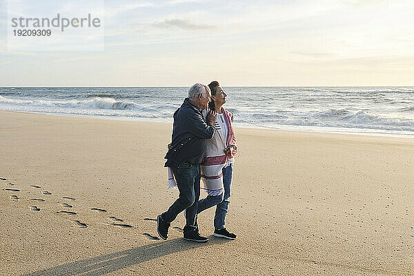 Liebevolles älteres Paar  das am Strand auf Sand spaziert