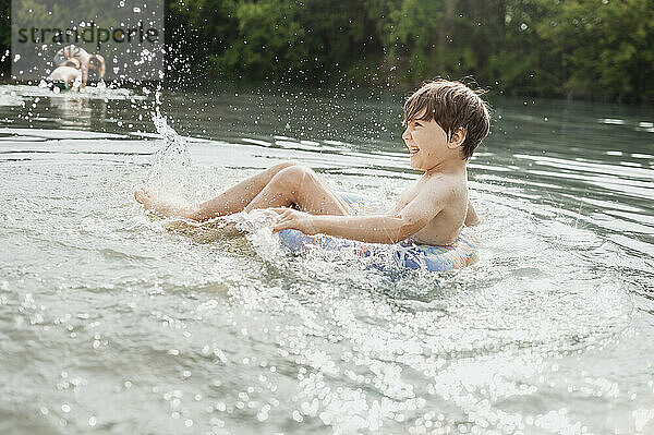 Fröhlicher Junge schwimmt im Wasser mit aufblasbarem Schwimmring