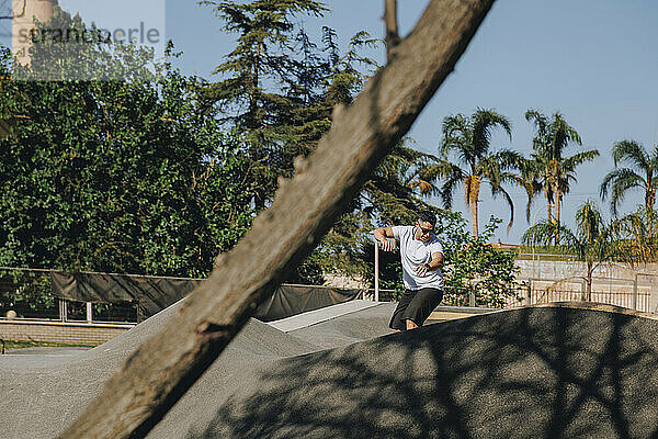 Reifer Mann übt mit Skateboard im Park