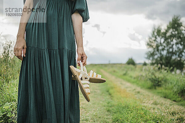 Frau steht mit Schuhen im Feld