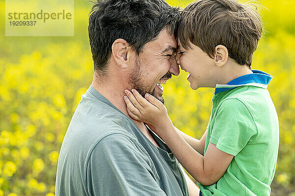 Glücklicher Vater umarmt Sohn auf dem Feld
