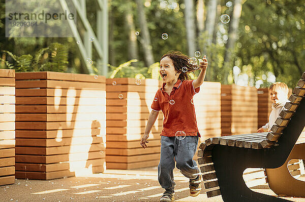Sorgloser Junge spielt mit Seifenblasen im Park