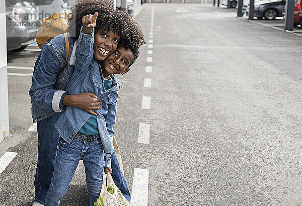 Glückliche junge Frau mit Sohn gestikuliert auf der Straße