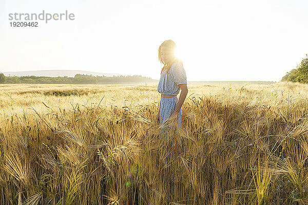 Back lit girl standing in wheat field