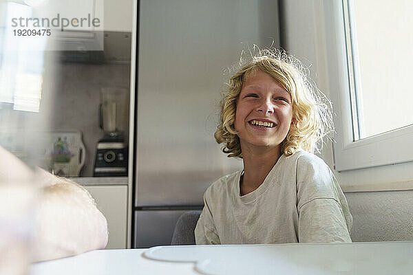 Lächelnder Junge sitzt in der Küche