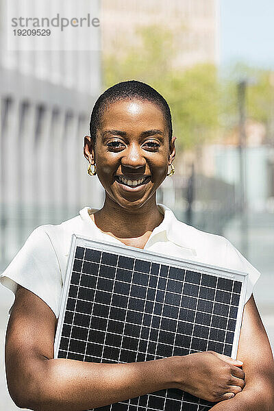 Glückliche junge Geschäftsfrau mit Solarpanel an einem sonnigen Tag