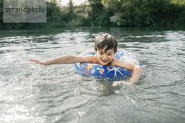 Happy boy with inflatable swim ring swimming in water