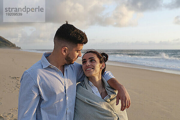 Romantischer Mann mit Arm um Freundin am Strand
