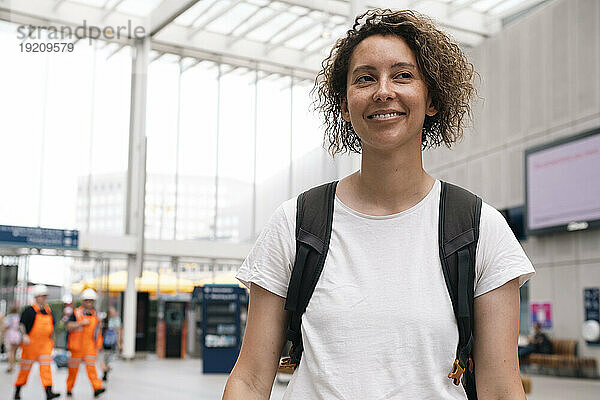 Lächelnde Geschäftsfrau  die am Bahnhof nachdenkt