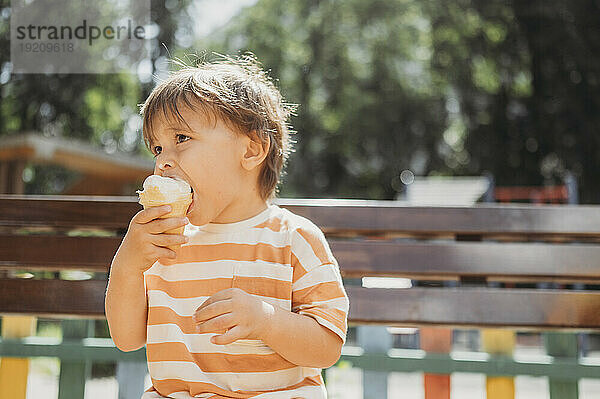 Nachdenklicher Junge isst Eis im Park