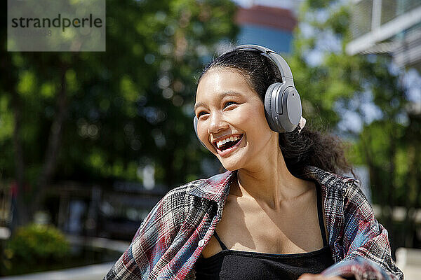 Happy student listening to music and laughing at sunny day