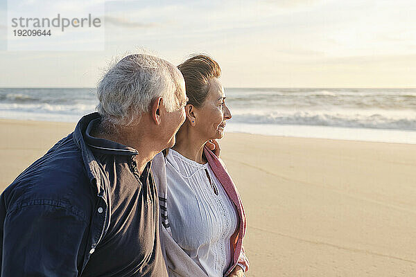 Lächelndes älteres Paar am Strand an einem sonnigen Tag