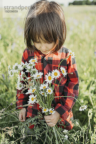 Junge hält Blumenstrauß im Feld