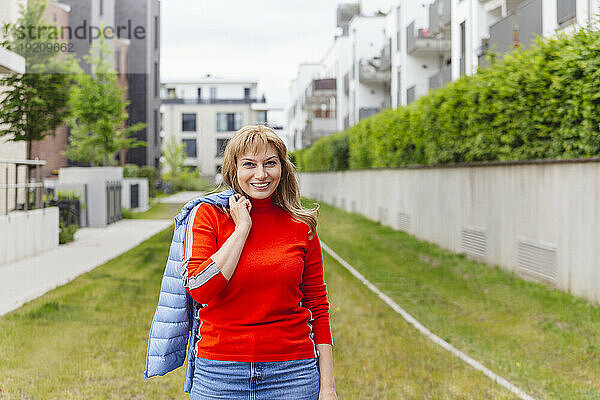 Lächelnde Frau im orangefarbenen Outfit mit Jacke