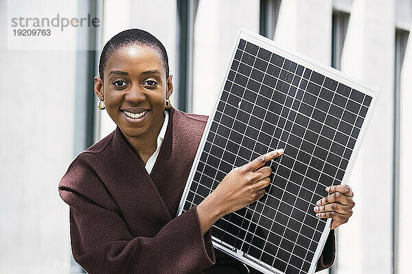 Glückliche Geschäftsfrau zeigt auf Solarpanel