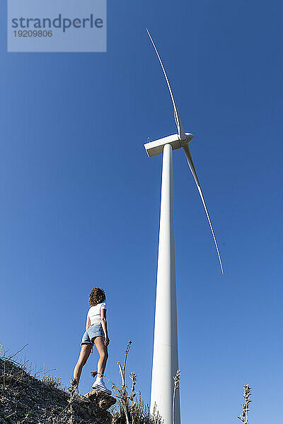 Frau steht vor Windkraftanlage