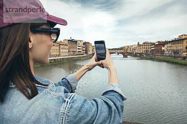 Frau fotografiert den Fluss Arno mit ihrem Smartphone