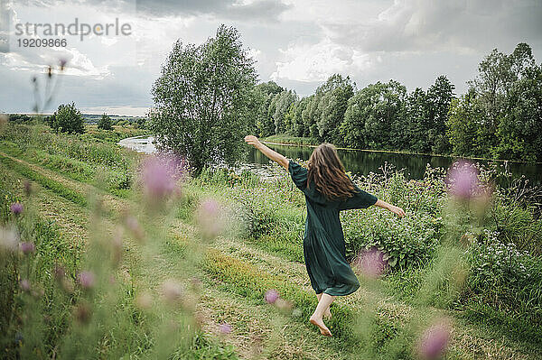 Frau mit langen Haaren tanzt im Feld