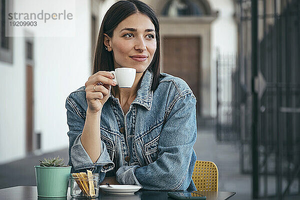 Lächelnde Frau in Jeansjacke beim Kaffee im Café