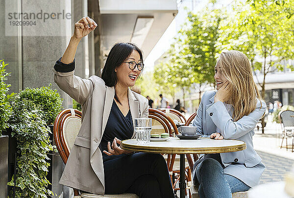 Geschäftsfrau diskutiert mit Kollegin im Straßencafé