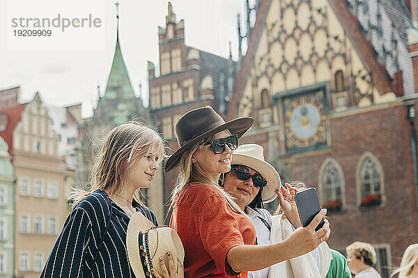 Glückliche Familie  die vor dem Gebäude ein Selfie mit dem Smartphone macht