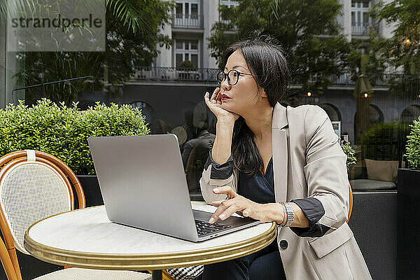 Businesswoman working with laptop on table at sidewalk cafe