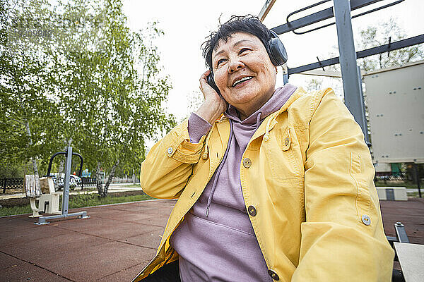 Lächelnde ältere Frau  die im Park Musik hört