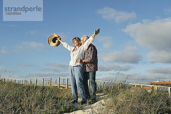 Glückliches älteres Paar  das an einem sonnigen Tag gemeinsam unter bewölktem Himmel genießt