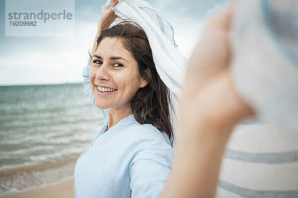 Fröhliche Frau mit Schal am Strand