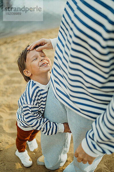 Mutter streichelt glücklichen Sohn am Strand