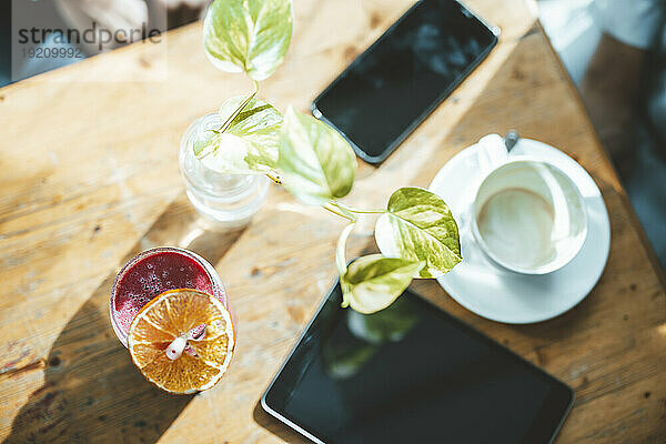 Tablet-PC und Smartphone mit Saft auf dem Tisch im Café