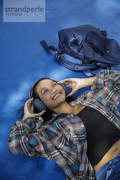 Happy student lying and listening to music