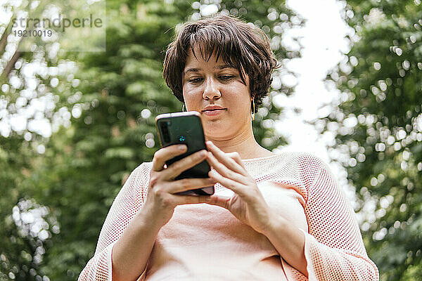 Junge Frau benutzt Smartphone im Park