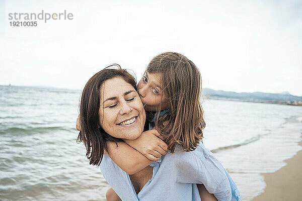 Mädchen küsst und umarmt Mutter am Strand
