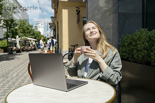 Geschäftsfrau genießt Kaffee mit Laptop auf dem Tisch im Straßencafé