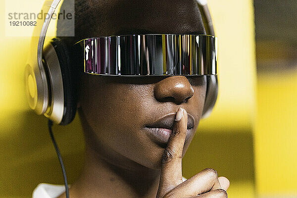Geschäftsfrau mit Finger auf den Lippen  Kopfhörer und Smart-Brille
