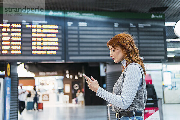 Frau benutzt Smartphone am Flughafen