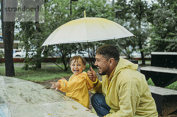 Vater und Sohn mit Regenschirm im Park