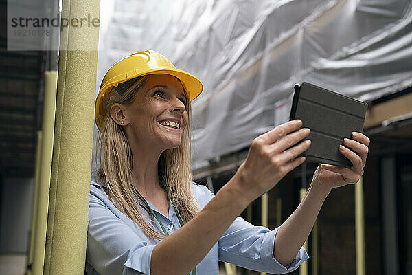 Glücklicher Ingenieur hält Tablet-PC auf der Baustelle