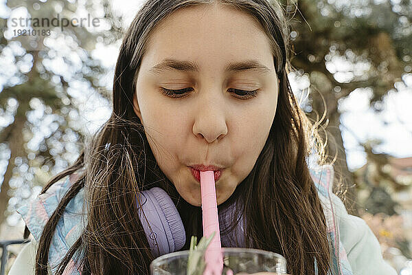 Mädchen nippt im Garten an Bubble Tea aus Stroh