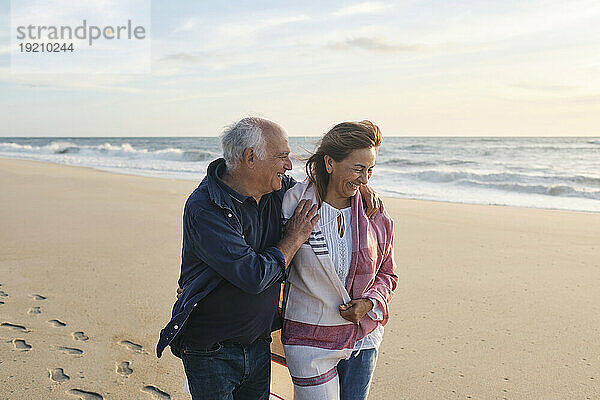 Glückliches älteres Paar  das gemeinsam am Strand spaziert