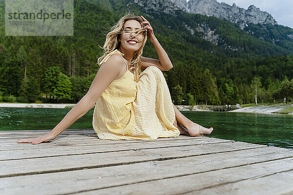 Beautiful woman sitting on pier by river