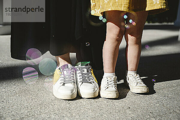 Mutter und Tochter stehen an einem sonnigen Tag mit Schuhen auf dem Boden