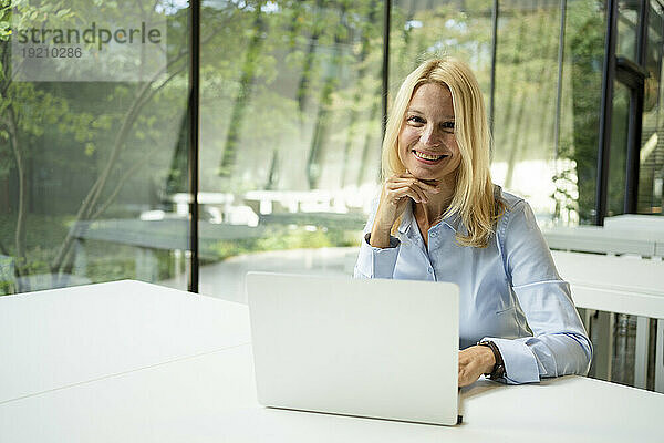 Lächelnde Geschäftsfrau sitzt vor Laptop